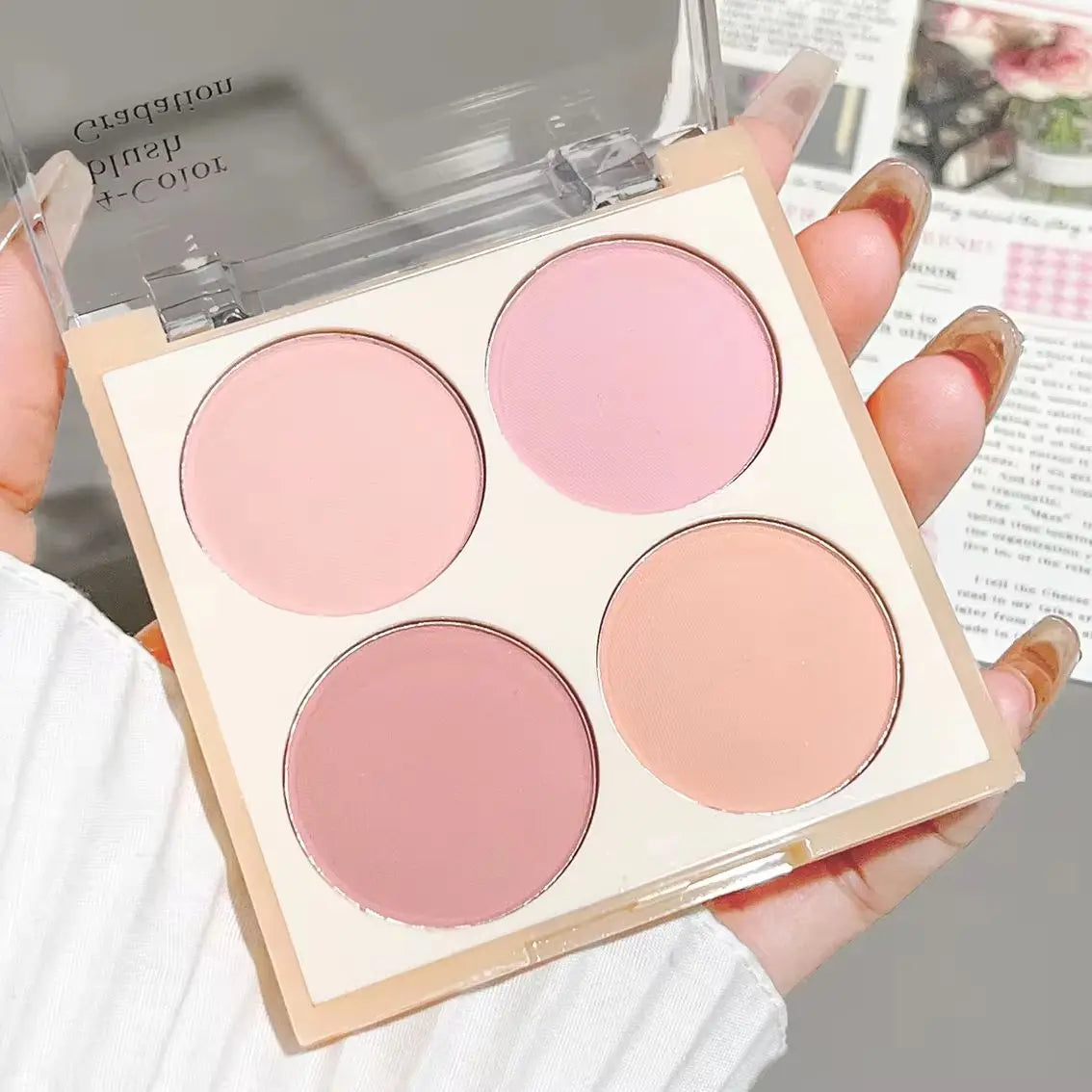 Palette de 4 blushs mats aux tons pêche et corail, fini poudré doux pour un maquillage naturel.