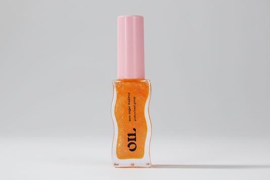 Huile à lèvres au miel texture gelée scintillante sur peau urbaine.