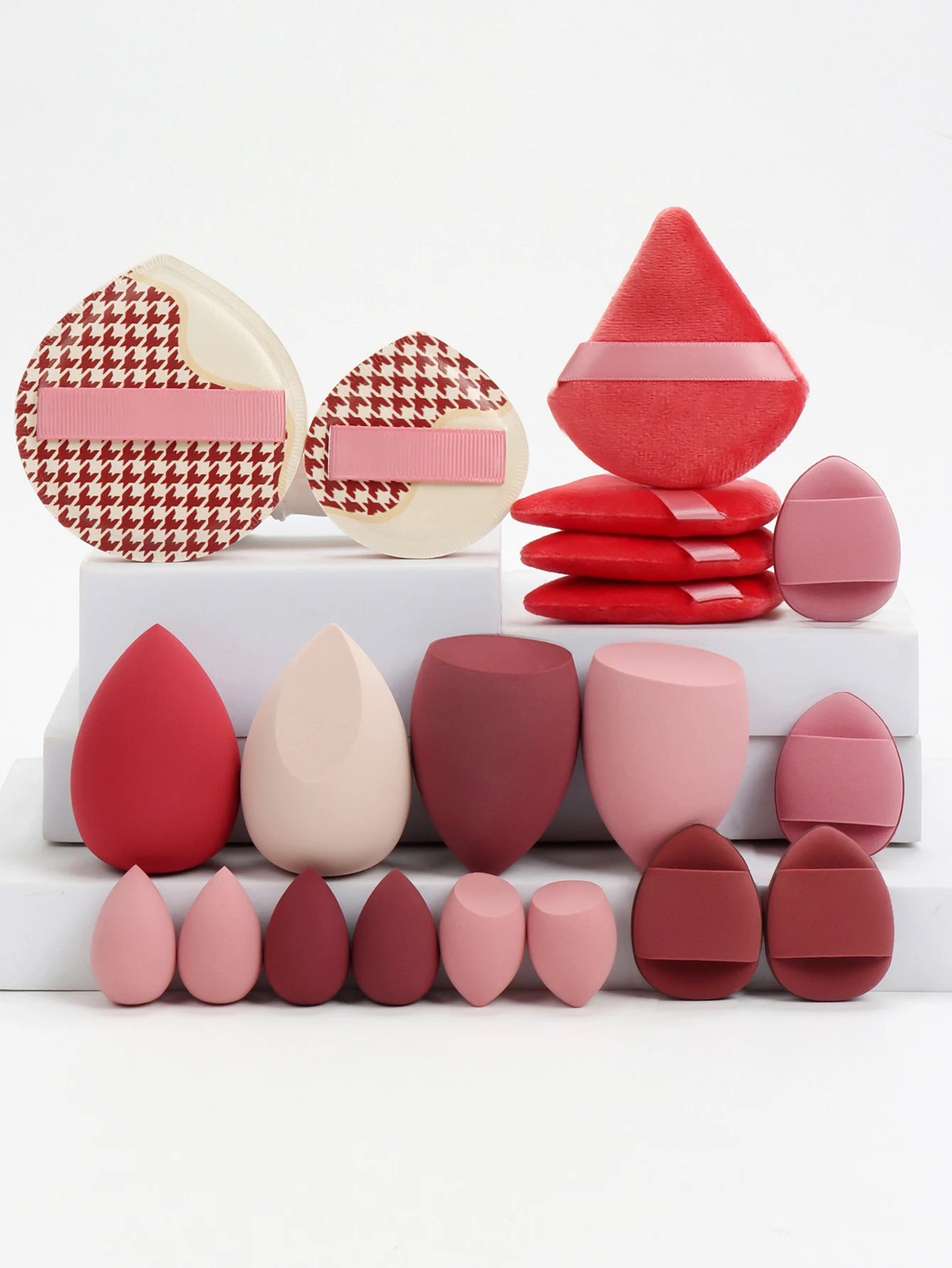 Collection de 20 éponges et houppettes de maquillage roses de différentes formes pour fond de teint et poudre.
