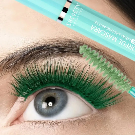 Application d'un mascara bleu cobalt sur des cils longs et recourbés, brosse haute précision et fini sans paquets.
