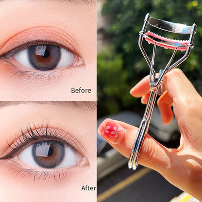 Recourbe-cils noir mat avec peigne séparateur intégré et coussinet en silicone rouge.
