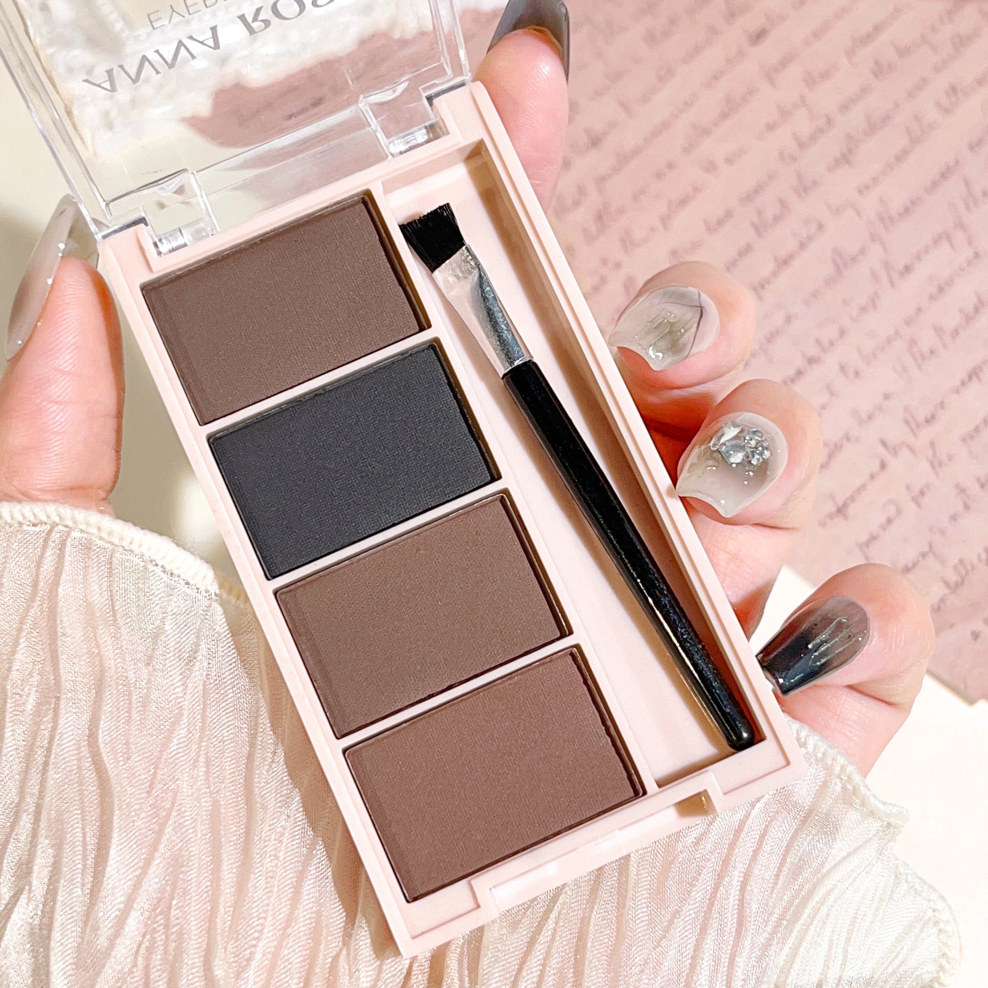 Palette de 4 poudres à sourcils mates (dégradés de gris et marron) avec ses pinceaux applicateurs intégrés.