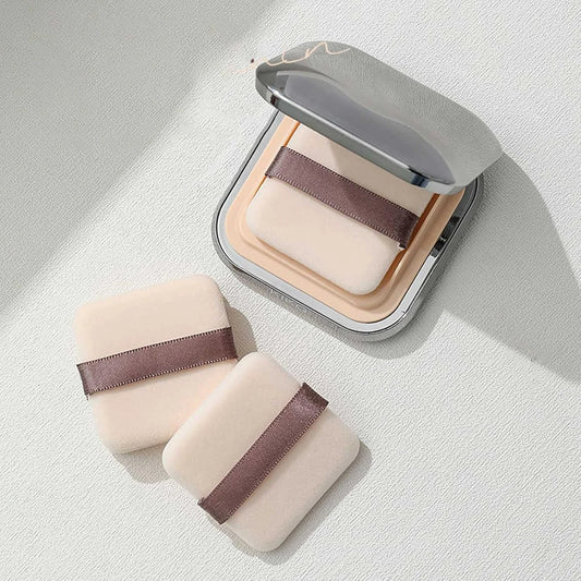 Lot de deux houppettes carrées en velours noir et blanc pour application de fond de teint et poudre libre.

